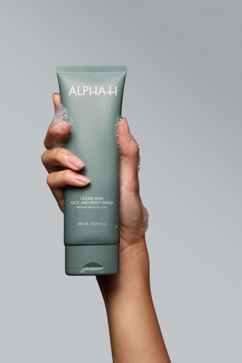 Alpha-H Clear Skin Face & Body Wash tube dans la main
