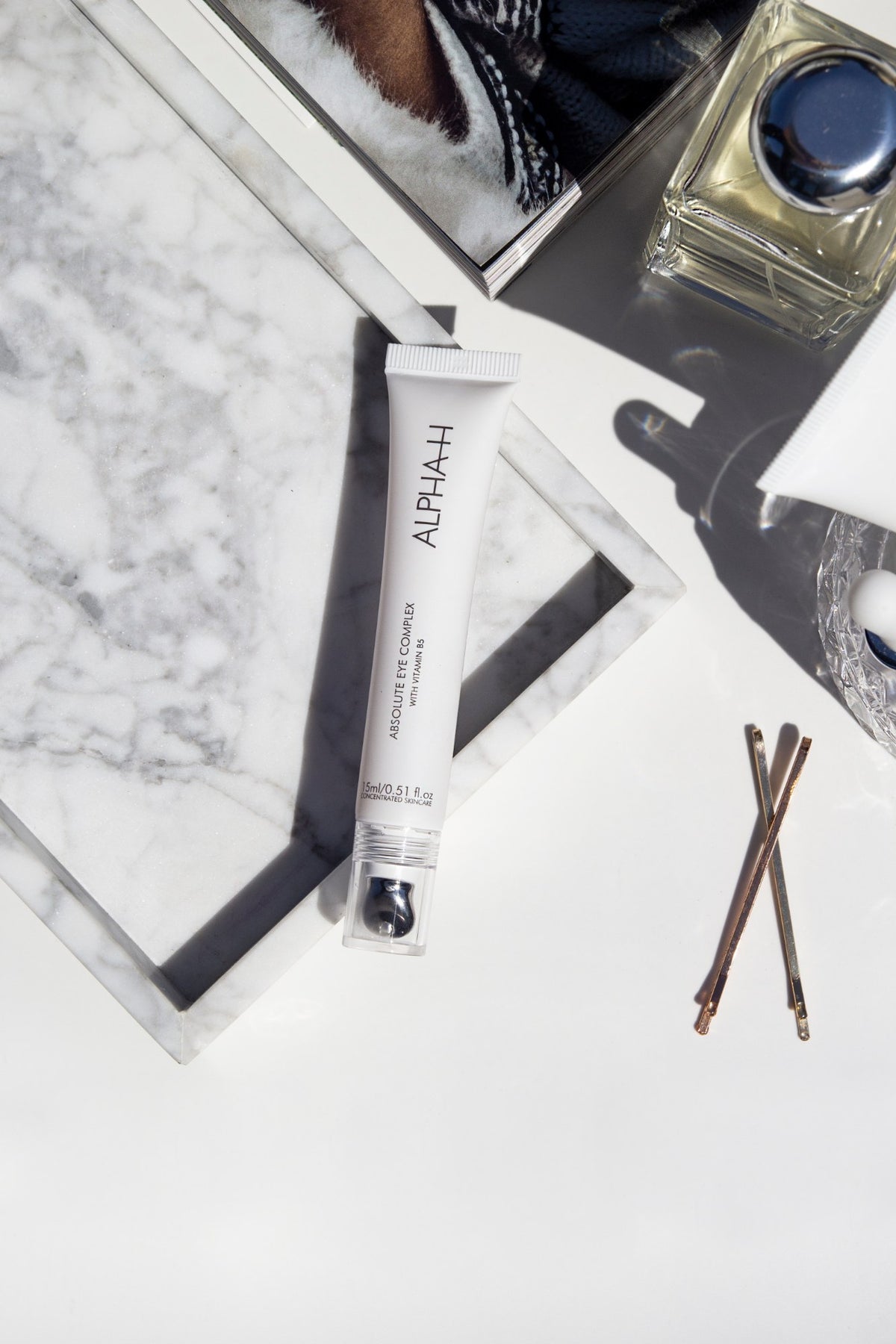 Alpha-H Absolute Eye Complex sur marbre avec des pinces à cheveux