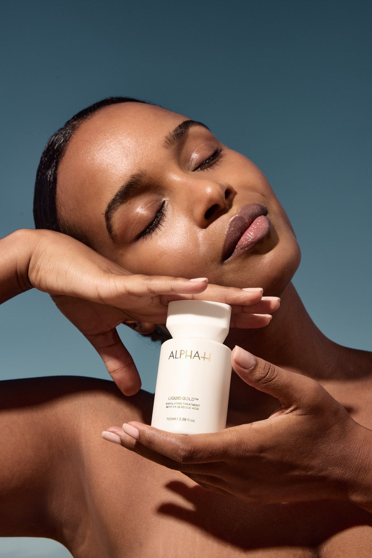 Alpha-H Liquid Gold Exfoliating Treatment modèle avec le flacon à la lumière du soleil