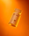 Alpha-H Liquid Gold + Vitamin C Exfoliating Treatment flacon sous une lumière orange