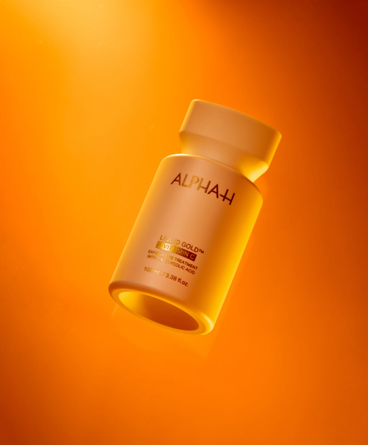 Alpha-H Liquid Gold + Vitamin C Exfoliating Treatment flacon sous une lumière orange