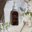 Oolaboo Super Foodies Matcha Infused Oil sur un linge de lin avec des fleurs