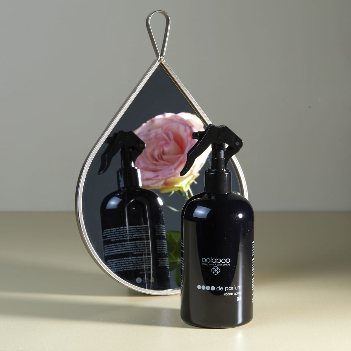 Oolaboo OOOO de Parfum Room Spray près d’un miroir avec une rose