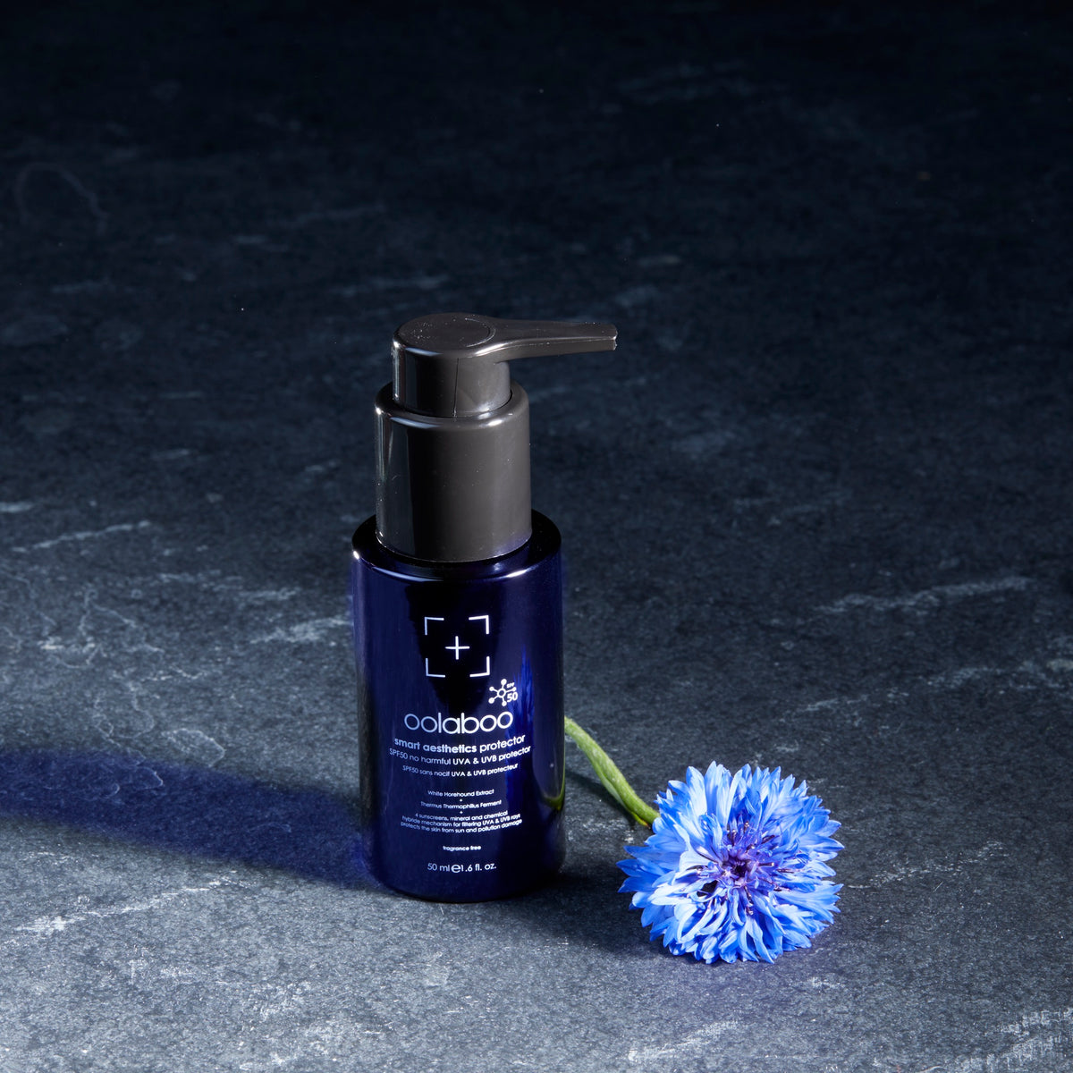 Oolaboo Smart Aesthetics SPF50 Protector flacon sur ardoise avec bleuet