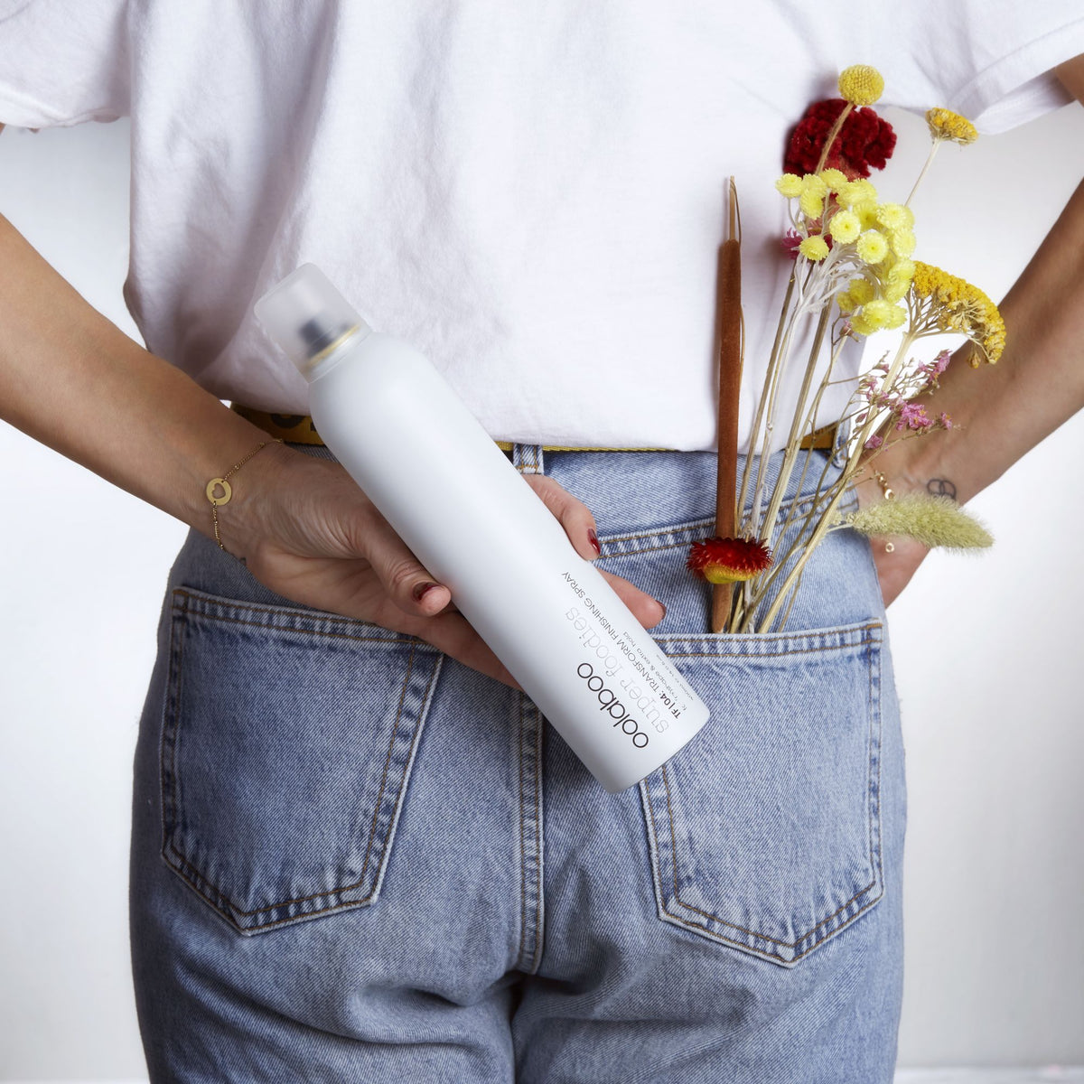 Oolaboo Super Foodies Transform Finishing Spray dans une poche arrière avec des fleurs