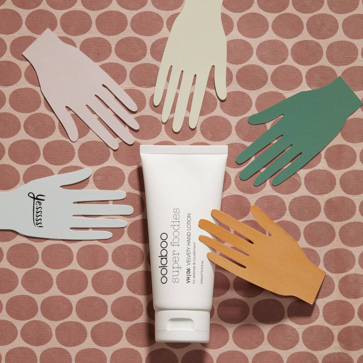 Oolaboo Super Foodies Velvety Hand Lotion entre des mains en papier